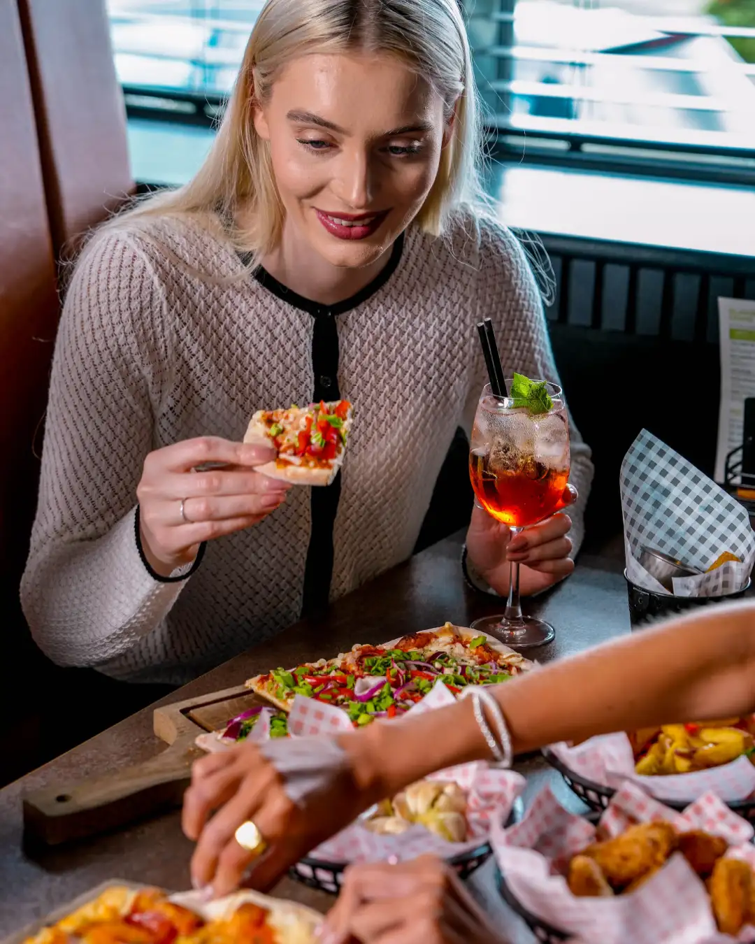 A woman eating pizza at Hukd golf as part of a commercial photography shoot