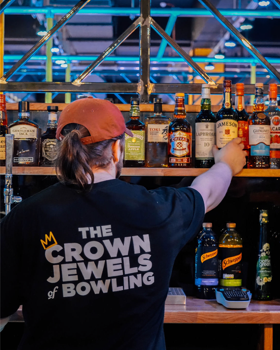 A bar tender at King Pins wearing a T-shirt designed by little green jesus
