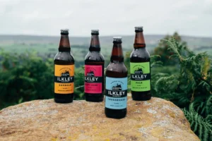 Ilkley Brewery Bottles designed by little green jesus sat on a rock over looking a field